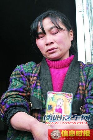 范远秀抱着女儿婴儿时的照片痛哭。她的女儿谭薇在此次事故中遇难。